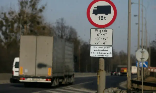 Znak zakazu ruchu dla ciężarówek powyżej 18t w określonych godzinach. Czy ciężarówki mogą jeździć w niedzielę? Ten znak odpowiada.
