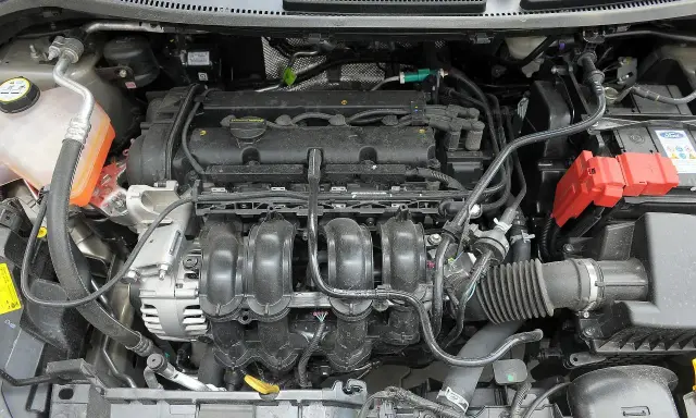 Silnik 1.6 HDI ile oleju? Widok komory silnika Forda, z widocznym kolektorem dolotowym, alternatorem i akumulatorem.