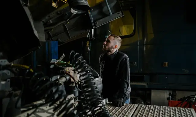 Mechanik analizuje przedmuchy w silniku diesla objawy, badając skomplikowane przewody i elementy ciężarówki w warsztacie.