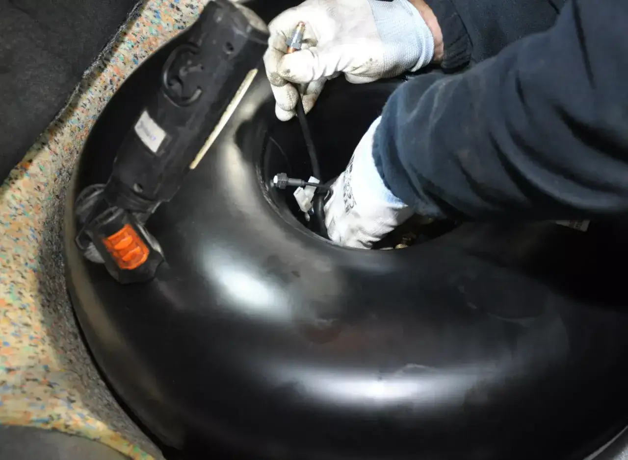 Ręce w rękawiczkach montują zawór do butli LPG. Poznaj koszt wymiany butli lpg i zadbaj o swoje auto.