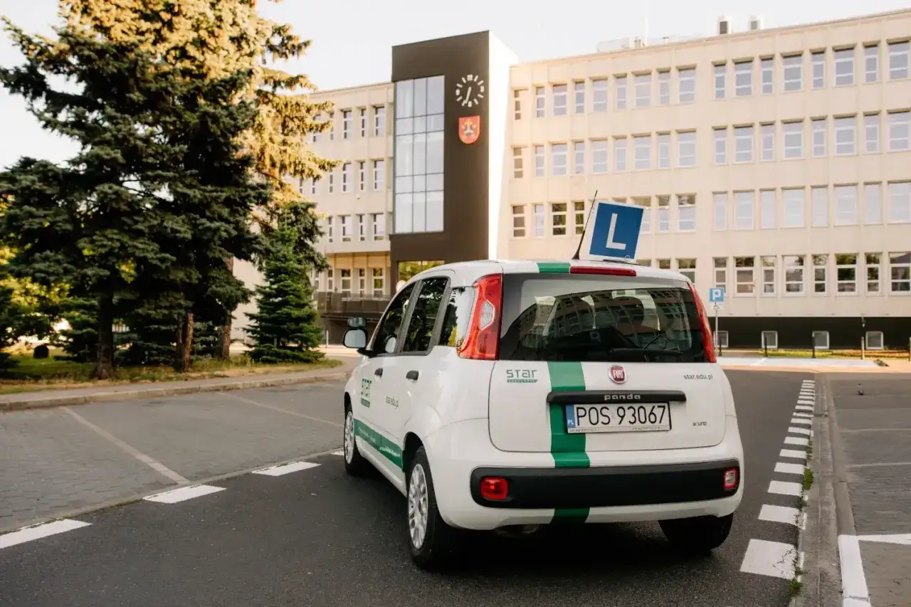Biały Fiat Panda z zielonym pasem i literą 