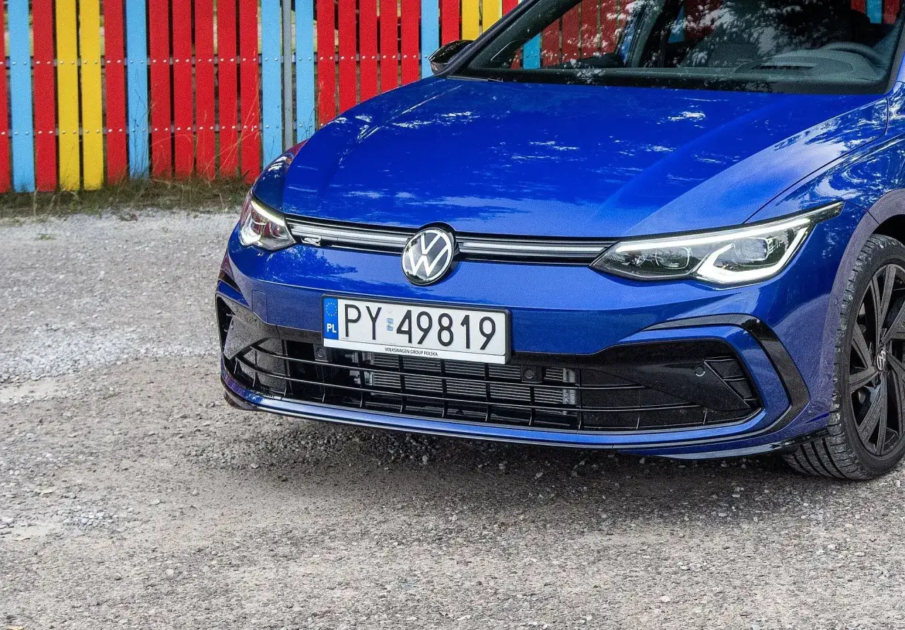 Niebieski Volkswagen z tablicą PY 49819, zaparkowany przed kolorowym płotem.