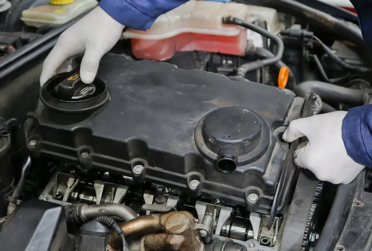 Mechanik w białych rękawiczkach sprawdza silnik. Może to być związane z nieszczelna odma objawy.