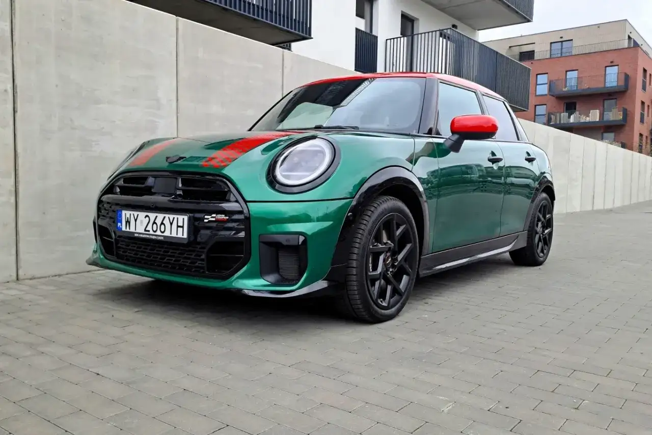 Zielony Mini Cooper z czerwonym dachem i pasami, zaparkowany na kostce brukowej. Zastanawiasz się, ile pali ten Mini Cooper?