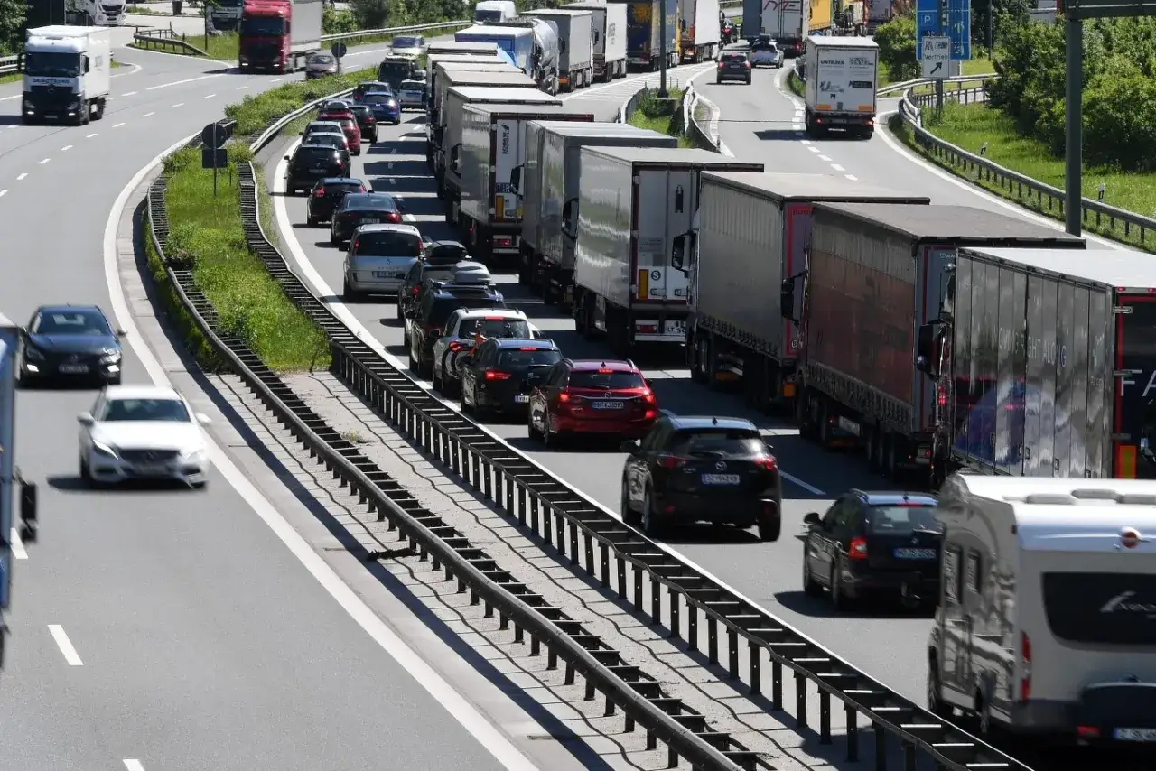 Korek na autostradzie, gdzie prędkość ciężarówki jest ograniczona przez tłok. Wiele pojazdów, w tym ciężarówki i samochody osobowe, stoi w długim sznurze.