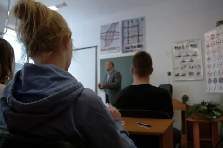 Nauka do egzaminu na prawo jazdy 3 miesiące przed 18. Uczniowie słuchają wykładu o przepisach drogowych.